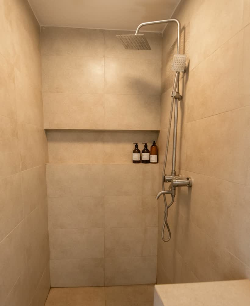 Walk-in heated shower with rainfall head and toiletries in the wall niche